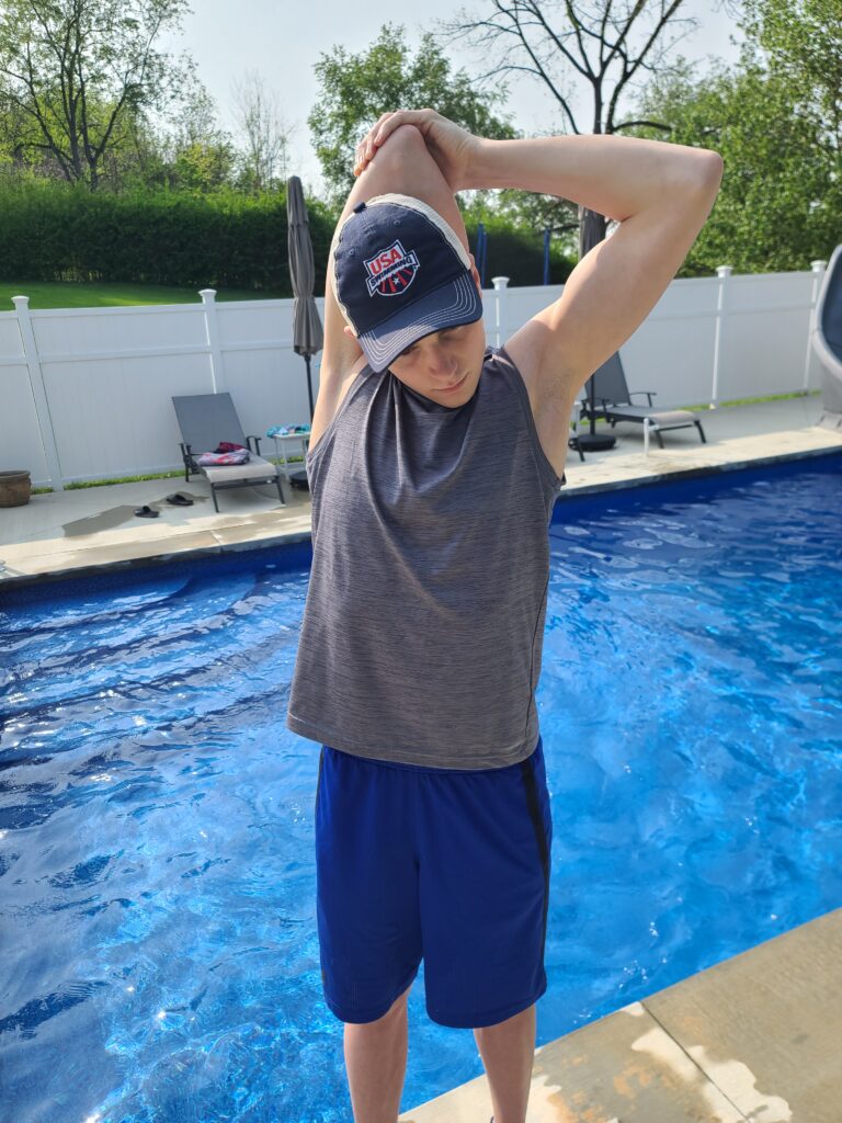 Il nuotatore competitivo, Alex Ailatis, che dimostra un allungamento di Latissimus dorsi per correggere la spalla del nuotatore.