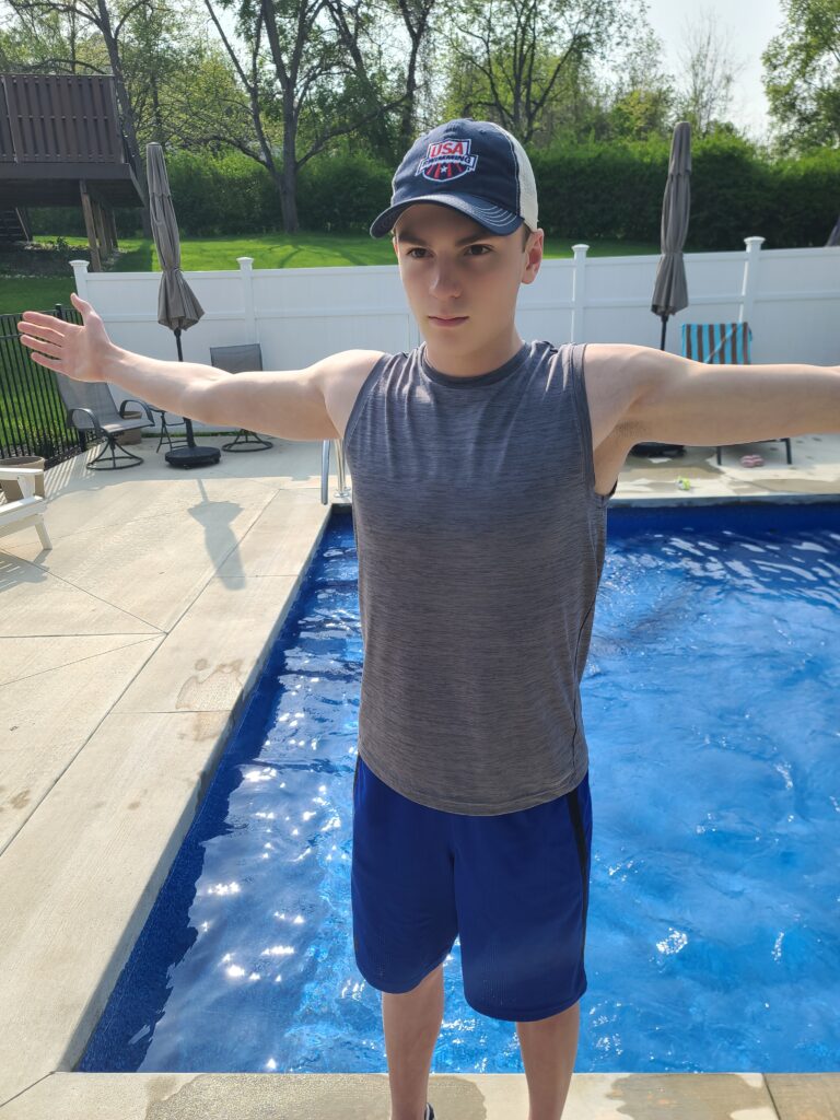 Il nuotatore competitivo, Alex Ailatis, che dimostra una spalla anteriore e un allungamento pettorale per correggere la spalla del nuotatore.